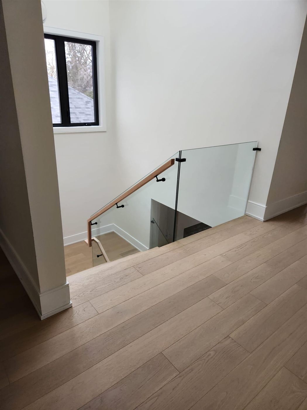 Frameless glass staircase railing with wood handrail