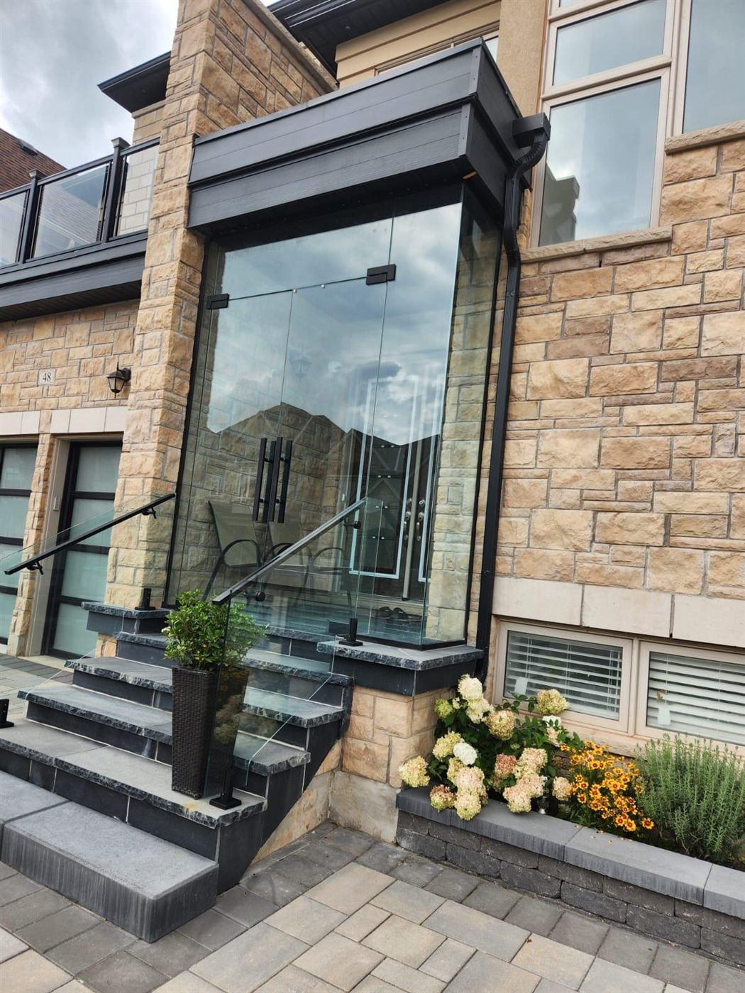 Glass sunroom addition with black entry railing