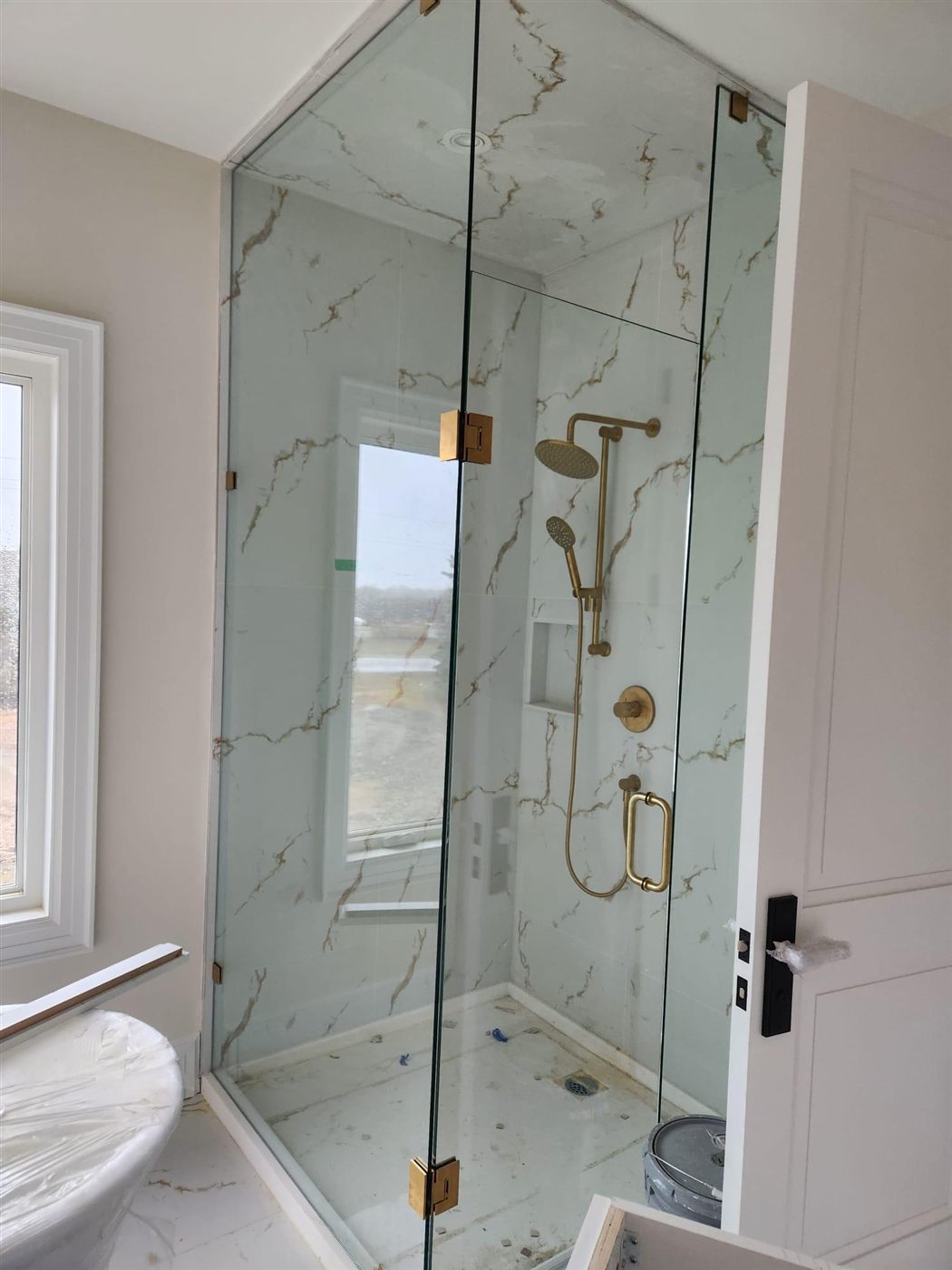 Walk-in glass shower with brass fixtures